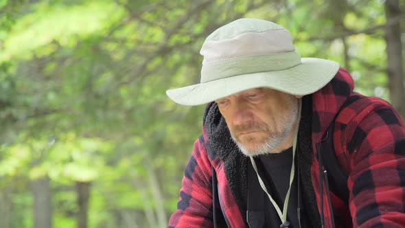 An older man looking at a map while hiking in a scenic forest in the mountains alt