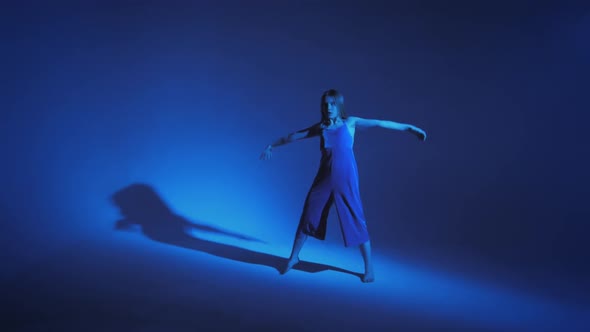 Young Stylish Girl Dancing in the Studio on a Colored Neon Background alt