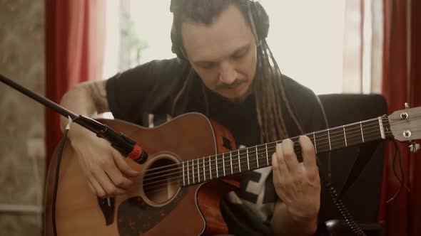 Musician with Dreadlocks Playing Guitar at Home