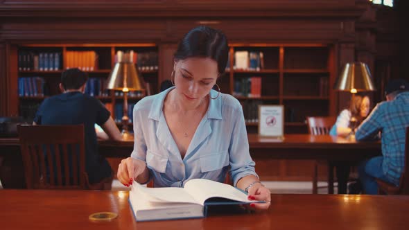 Young woman reading a book in the library alt