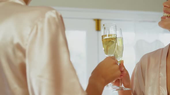 Excited bridesmaids in nightdress and hair rollers toasting a glass of champagne 4K 4k alt