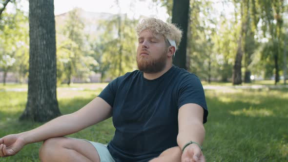 Obese Man Practicing Yoga Meditation in Park alt