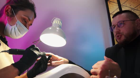 A Business Man Having His Nails Done in Salon and Talking with His Master alt