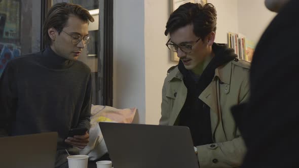 Businessmen Having Meeting in Cafe. Businessman Browsing Internet on Smartphone alt