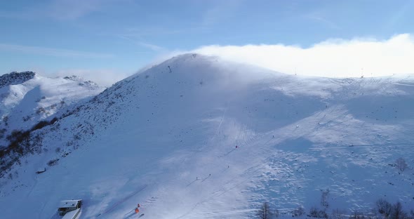 Orbit Aerial Over Winter Snowy Mountain Top Ski Tracks Resort with Skier People Skiing