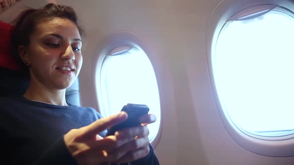 Woman on a plane using mobile phone during flight