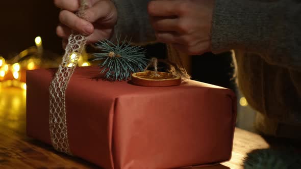 Closeup of Female Hands Decorates Christmas Present alt