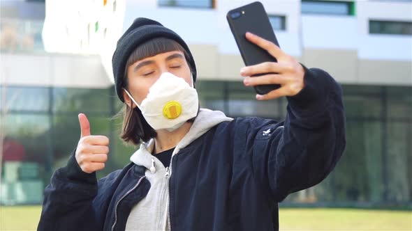 Stylish Hipster Girl Doing Selfies in Respiratory Mask on the Modern Street alt