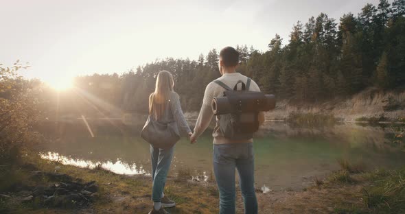 Male Female Travelers Standing on Shore Enjoy View of Beautiful Lake. Young Couple Traveling alt