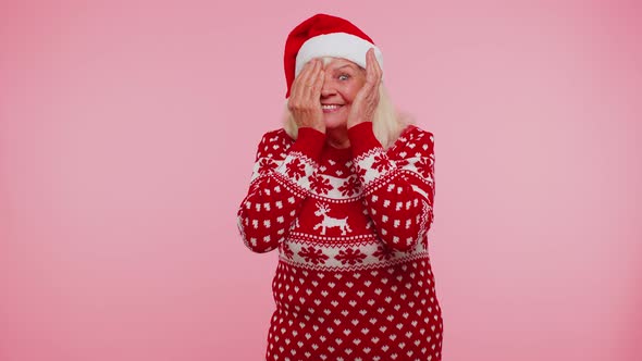 Woman in Sweater Santa Christmas Hat Fooling Around Having Closing Eyes with Hand and Spying Through alt