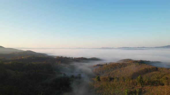4K aerial view over a misty mountainous area. The great golden sun in the morning alt
