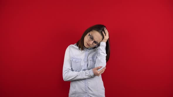 A Young Woman with Glasses Has a Headache and Holds It in Her Hands alt