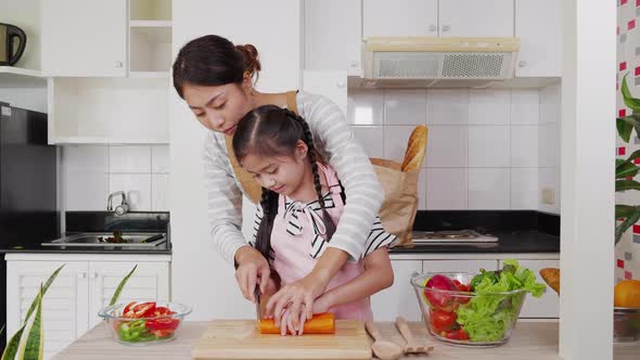 Asian mother and daughter cooking and cutting vegetables together for preparing salad alt