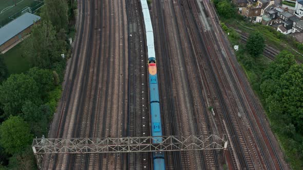 Pan up drone shot from expansive railway train tracks to London Skyline alt