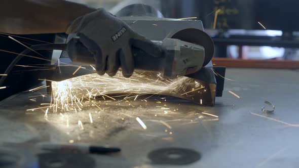 Worker cutting a part of oven in workshop alt