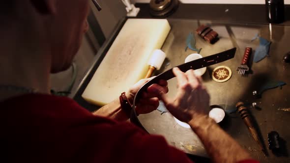 A Man Lubricates the Edge of a Leather Belt alt