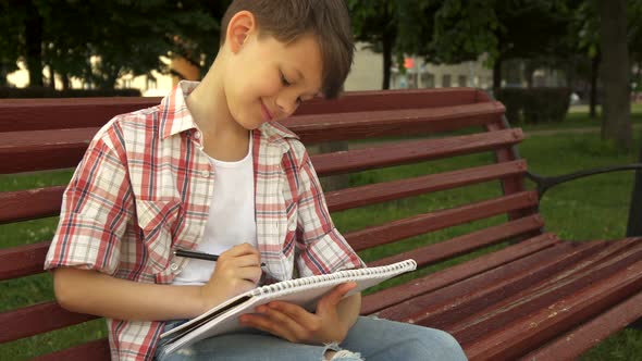 Little Boy Notes in Exercise Book on the Bench alt