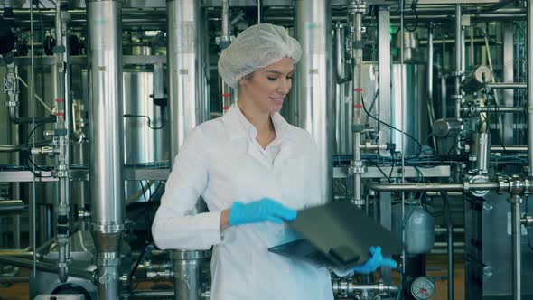 Female Worker with a Laptop Is Standing in a Factory Unit alt