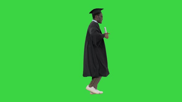 Excited African American Male Student in Graduation Robe Dancing with His Diploma While Walking on a alt