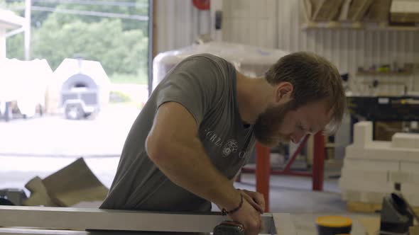 Medium shot of worker drilling holes in sheet metal alt