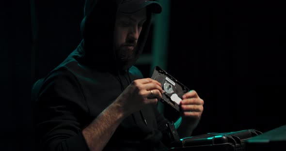 A Bearded Middleaged Hacker in a Black Hooded Sweatshirt Takes a Stolen Disk with Secret alt
