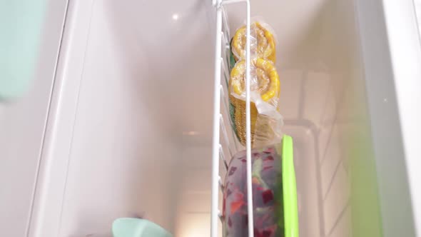 Woman Takes Out and Lies Back of the Freezer Chopped Vegetables alt