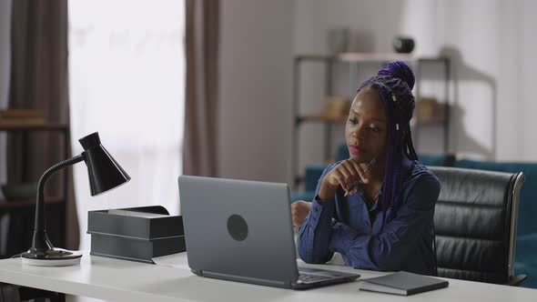Afroamerican Woman is Looking on Screen of Laptop and Listening Learning Webinar or Online Lecture alt