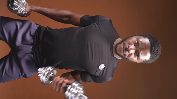 Athletic AfricanAmerican Man Training with Dumbbells on an Isolated Dark Background