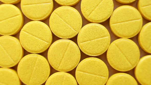 Medical yellow pills on rotating table, close up