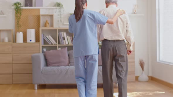 Beautiful doctor helping old man at clinic. Holding a senior patient with walking stick. Elder man u alt