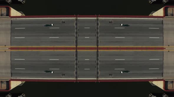 Top Down Ascending Footage of Cars Passing on Bridge Over Water Symmetrical Composition alt