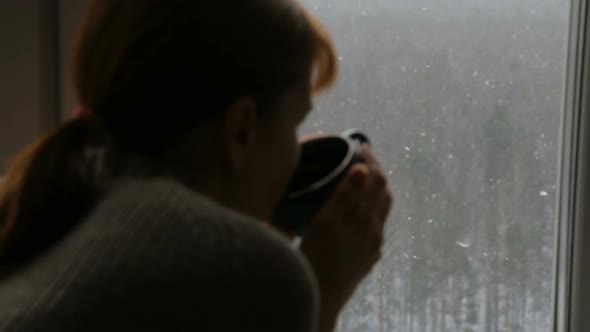 Woman drinking tea near the window