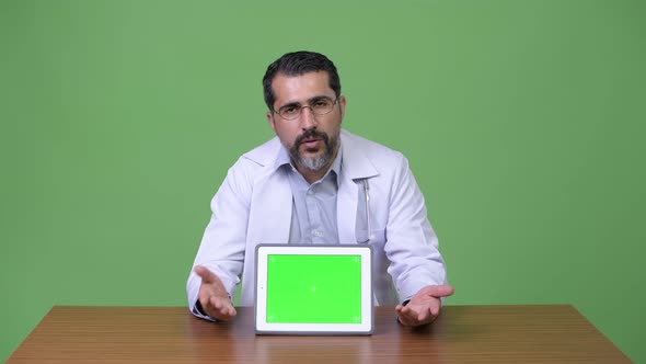 Handsome Persian Bearded Man Doctor Talking While Showing Digital Tablet
