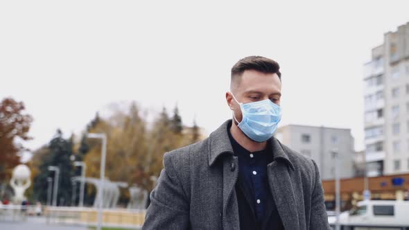 Young businessman is posing outdoor with a strong expression and facial mask. alt