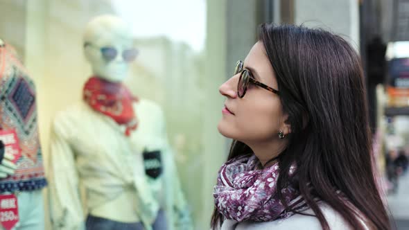 Medium Closeup Enthusiastic Buyer Pretty Woman Looking at Showcase of Boutique From Outdoor alt