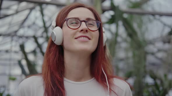 Portrait of Modern Young Woman with Red Hair, Big Headphones, Glasses