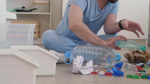 Man Sitting Floor in Kitchen and Sorting Trash alt