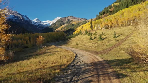 Flying over dirt road winding through the Utah wilderness during Fall alt