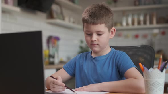 Smart Little Boy Uses Laptop for Video Call with His Teacher. Screen Shows Online Lecture