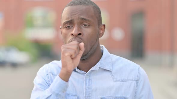 Outdoor Portrait of Sick Young African Man Coughing alt