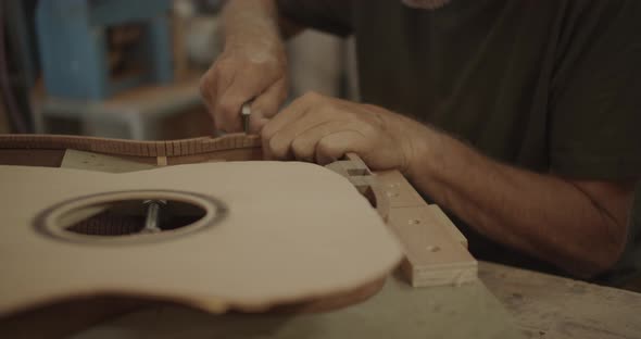 Luthier cutting cracks in a guitar mold