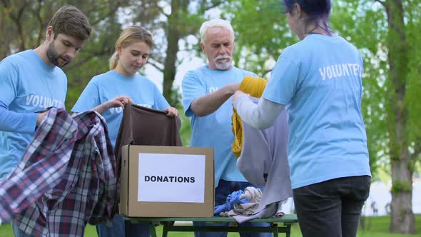 Volunteers Sorting Clothes Putting in Donation Box, Philanthropic Organization alt