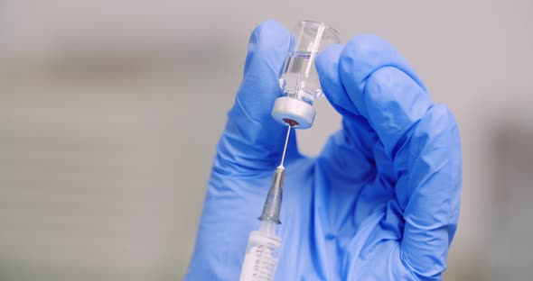 Extreme Close Up of Hand Holding Syringe and Vaccine in Hand in Laboratory. alt