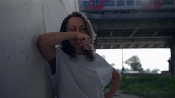 a Female Portrait Against the Background of a Railway Bridge with Passing Vehicles is Out of Focus alt