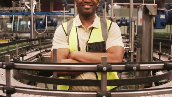 Portrait of worker standing with arms crossed near production line alt