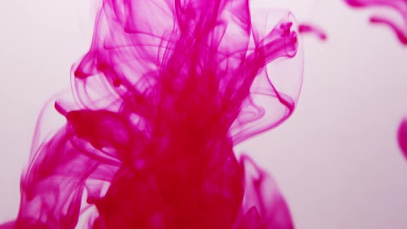 Red ink squirted into water as it swirls around alt