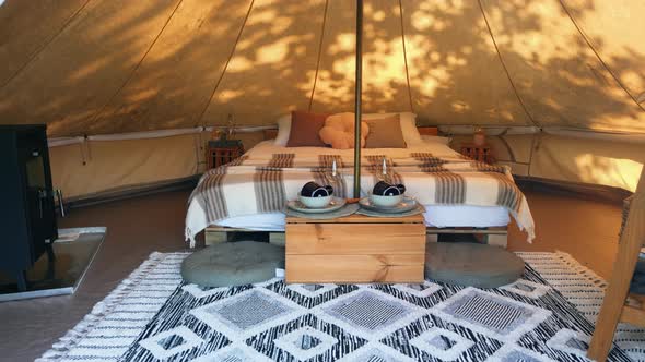 Interior of a glamping tent with chairs outside, nature, green grass and trees, trail alt