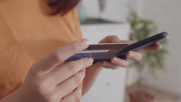 Young Asian Woman hand holding credit card using a digital mobile device and Buying online alt
