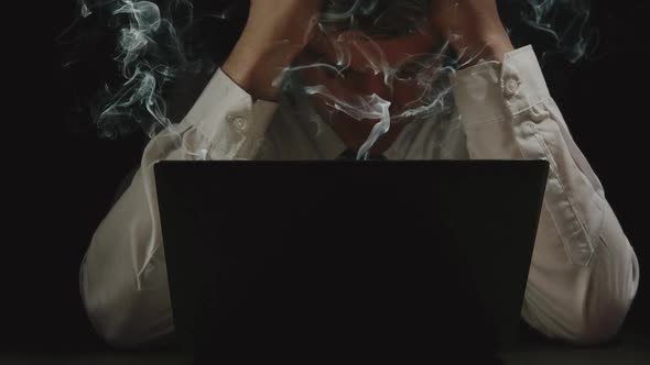 Businessman Is Grabbing His Head In Front Of The Smoking Laptop