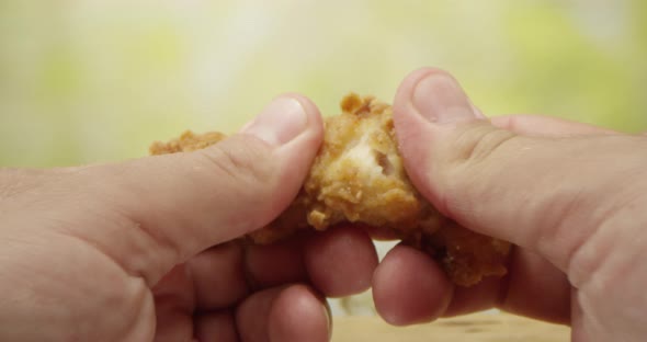 Male Hands Shred A Slice Of Fried Chicken Strip In Two Pieces On A Kitchen Table With Dolly Pushing alt
